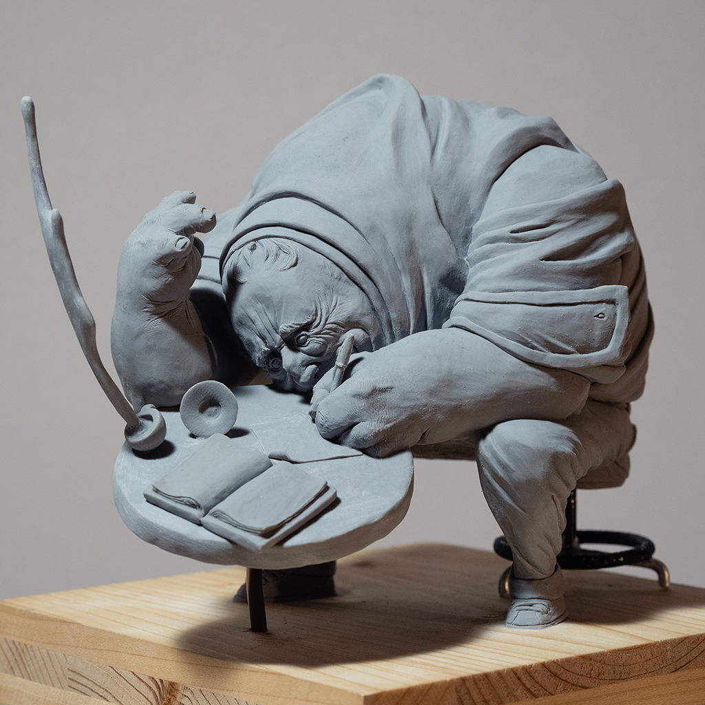 Sculpture de l'artiste Teddy Ros "café-créa" 2022, sculpté en pâte polymère , représentant un gros personnage assis sur un tabouret en train d'écrire dans son petit carnet, alors que sa tasse de café vol en éclat image 2