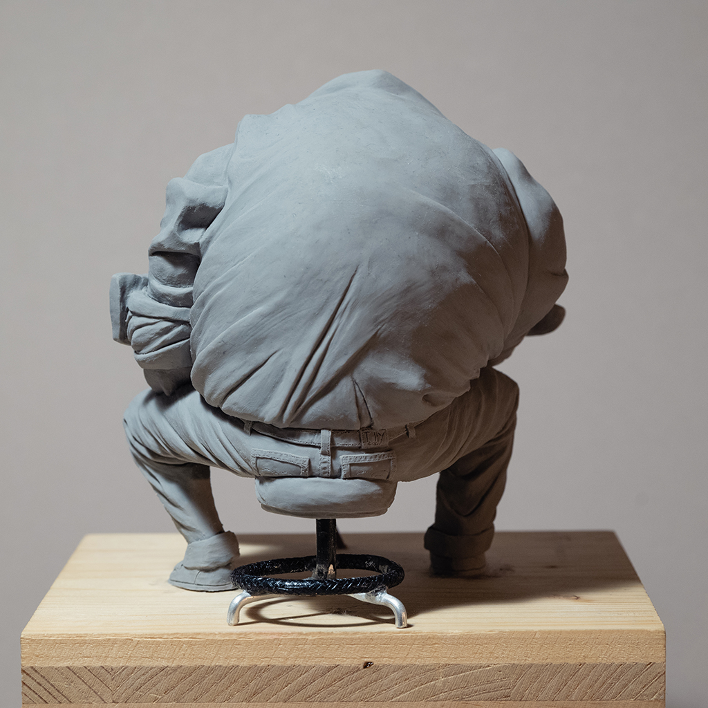 Sculpture de l'artiste Teddy Ros "café-créa" 2022, sculpté en pâte polymère , représentant un gros personnage assis sur un tabouret en train d'écrire dans son petit carnet, alors que sa tasse de café vol en éclat image 7